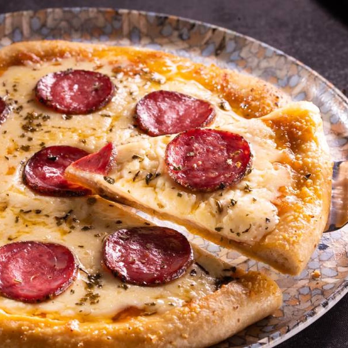 Ahşap tahta üzerinde dilimlenmiş sucuklu pizza